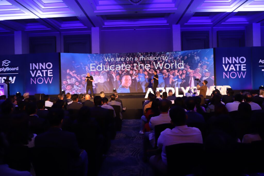 A lit stage at TRW 2023, featuring a large image captioned "we are on a mission to educate the world."
