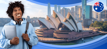 A male international student carrying a bag and a laptop looks upward, toward a framed image of the Sydney Opera house - a large building with a roof shaped like stacked sails on a ship.